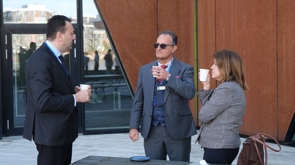 Three people drinking coffee outside and networking