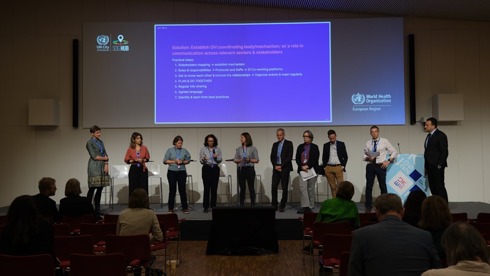 Group presenting on stage in front of power point presentation