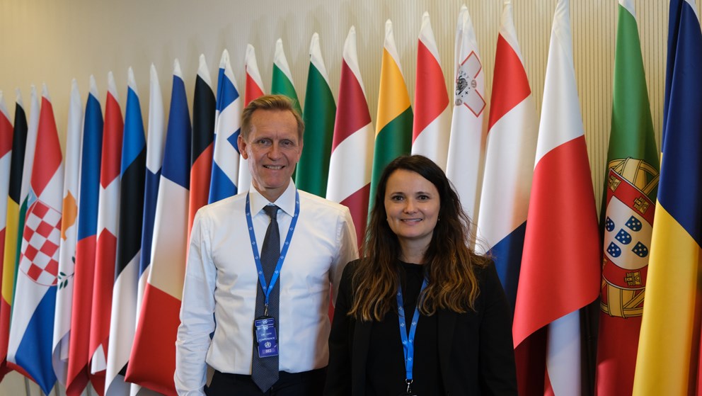 Man and woman standing in front of flags